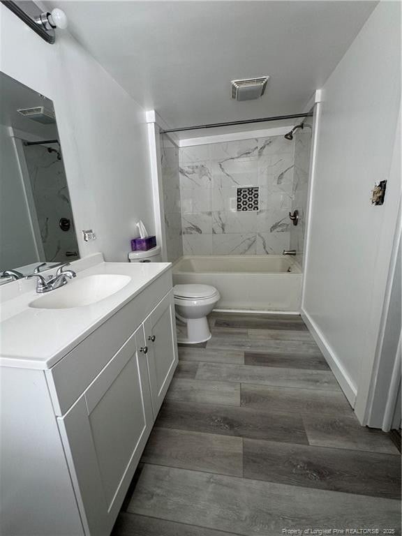 bathroom with visible vents, vanity, wood finished floors, toilet, and shower / tub combination