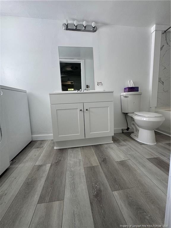bathroom featuring vanity, baseboards, wood finished floors, and toilet