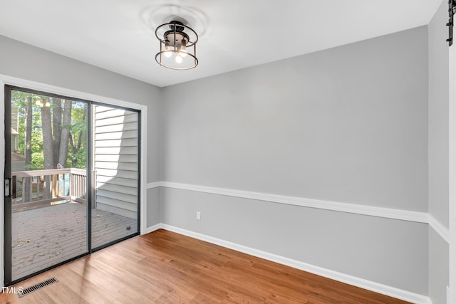 6513 Hearthstone Dr, Raleigh, NC 27615 - empty room featuring wood finished floors, baseboards, a chandelier, and a barn door