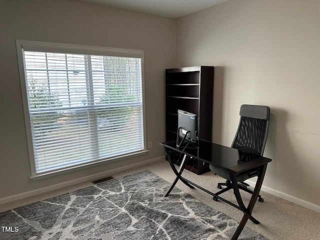 carpeted office space featuring baseboards and visible vents