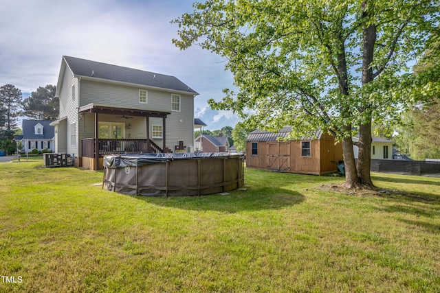 rear view of property with a storage unit, a lawn, and a covered pool