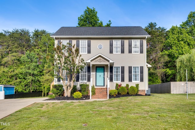 colonial inspired home featuring a front lawn, fence, and cooling unit