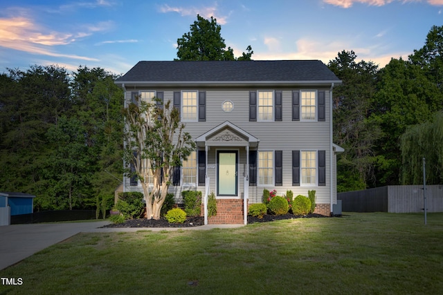 colonial-style house featuring a yard and fence