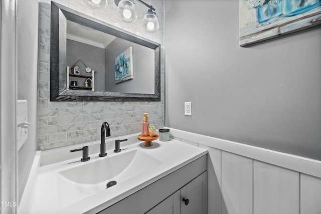 bathroom featuring vanity, crown molding, and tasteful backsplash