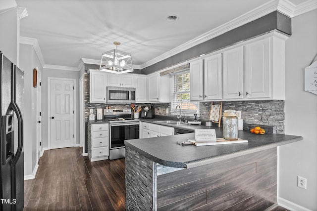 kitchen featuring white cabinetry, dark countertops, appliances with stainless steel finishes, and a sink
