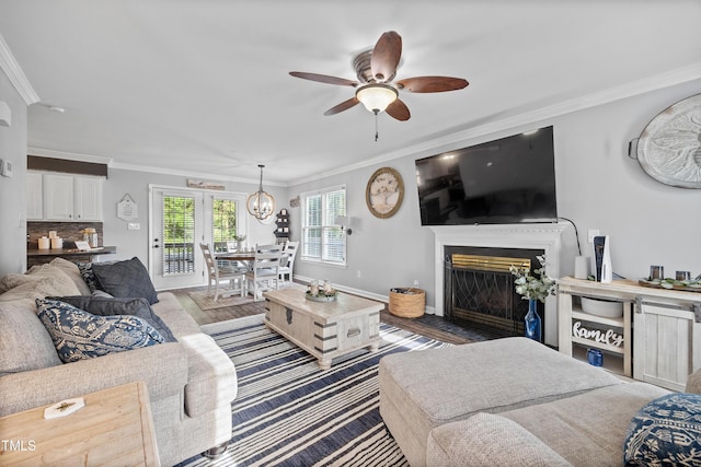 living area with crown molding, a fireplace with flush hearth, baseboards, and ceiling fan