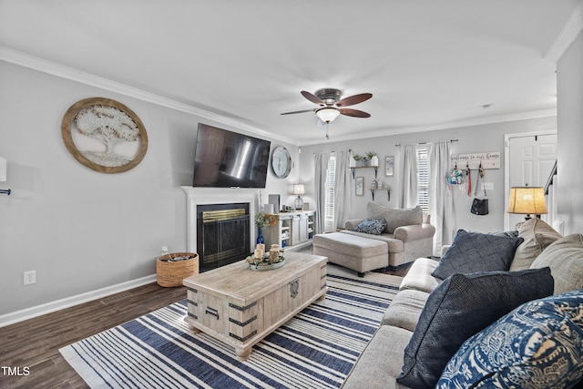 living area with crown molding, a fireplace, a ceiling fan, baseboards, and wood finished floors