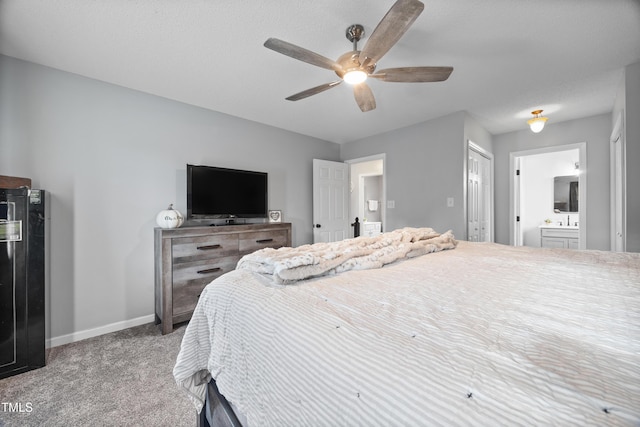 bedroom featuring carpet floors, a sink, baseboards, ensuite bathroom, and a ceiling fan