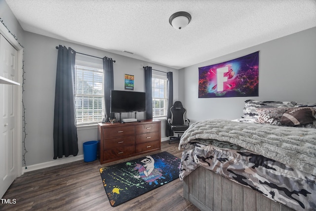 bedroom featuring wood finished floors, baseboards, a textured ceiling, and visible vents