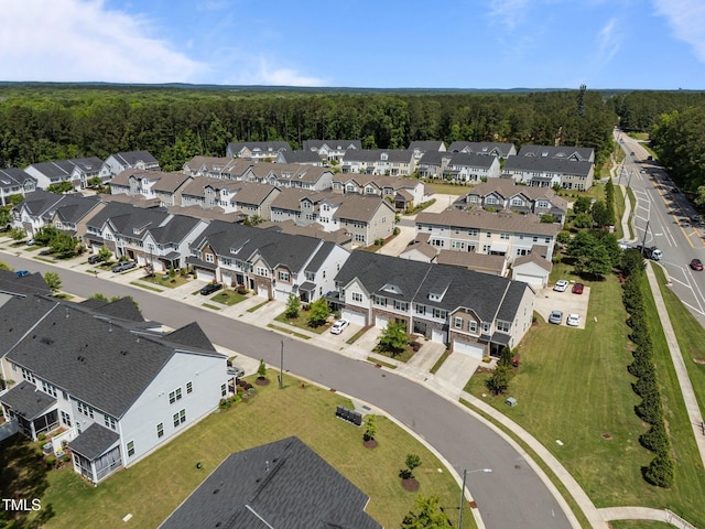 view of property location with nearby suburban area and a forest