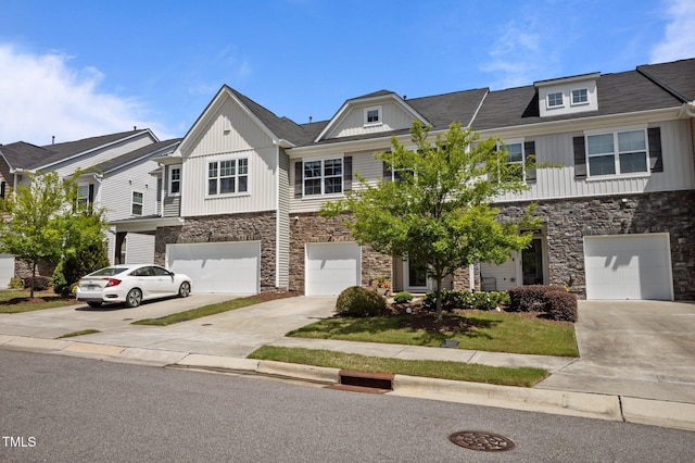 multi unit property featuring stone siding, driveway, and an attached garage