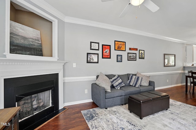 living area featuring baseboards, crown molding, ceiling fan, and wood finished floors