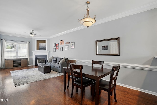 dining room with dark wood-style flooring, a ceiling fan, and ornamental molding