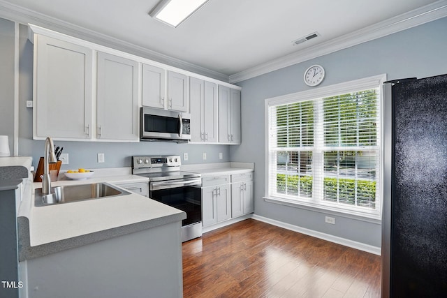 kitchen featuring a sink, stainless steel appliances, dark wood-type flooring, crown molding, and light countertops