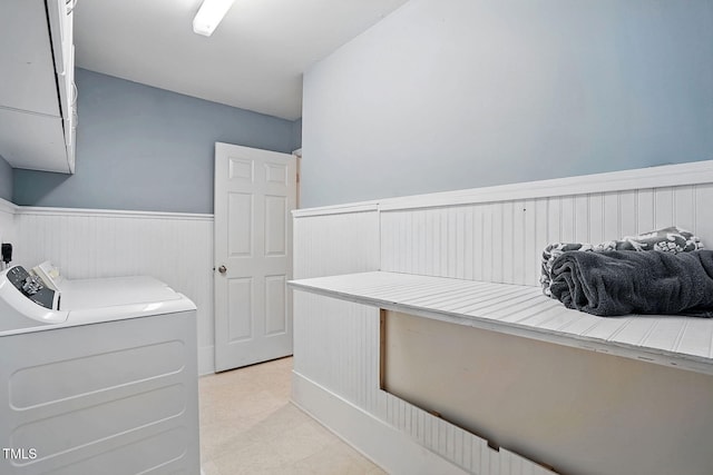 interior space featuring laundry area, wainscoting, and stacked washer and dryer