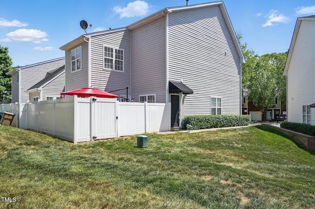 back of property with a lawn, fence, and a gate