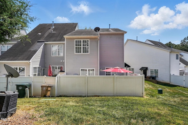 rear view of house featuring fence and a lawn