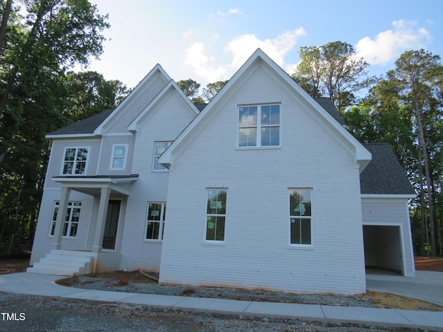 view of front of property with brick siding, a garage, roof with shingles, and concrete driveway