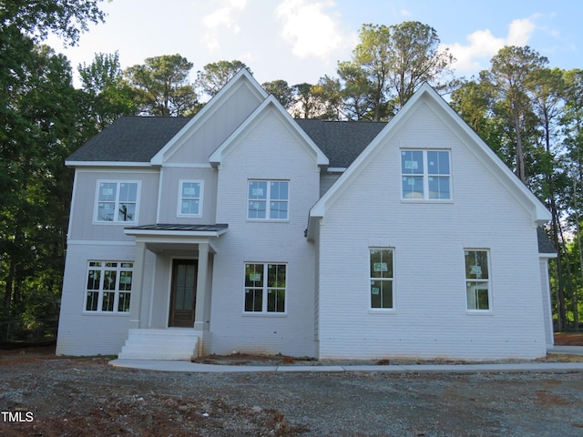 view of front facade featuring board and batten siding and roof with shingles