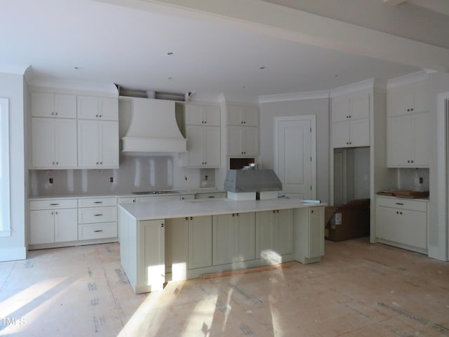 kitchen with a spacious island, white cabinets, custom exhaust hood, and stovetop