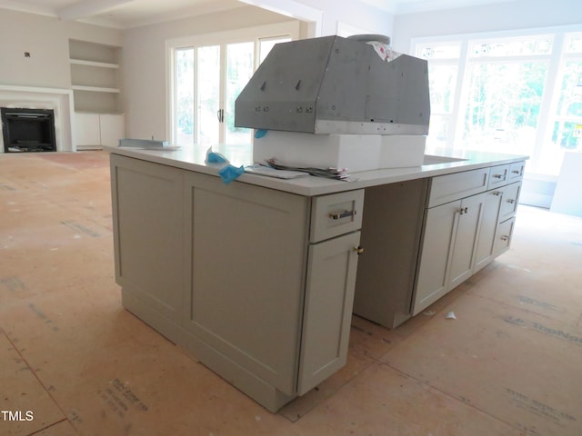 kitchen featuring plenty of natural light, built in features, white cabinets, and a fireplace