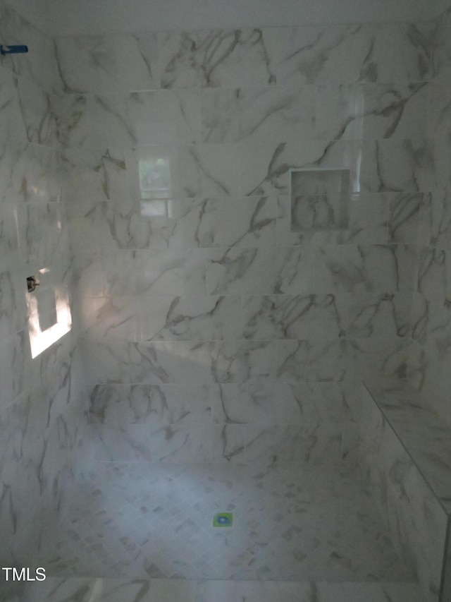bathroom featuring a marble finish shower