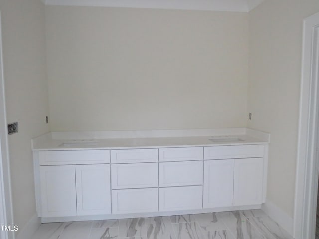 bathroom featuring baseboards, marble finish floor, and dual sinks