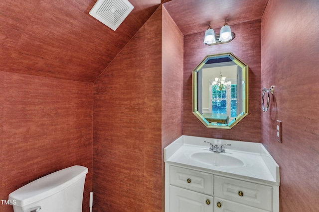bathroom featuring toilet, vaulted ceiling, vanity, and a chandelier