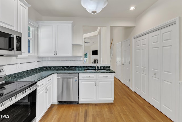 kitchen with appliances with stainless steel finishes, a sink, white cabinets, light wood-type flooring, and recessed lighting