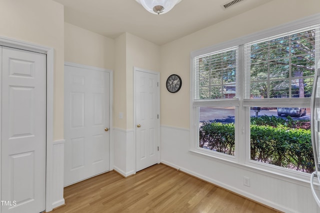 spare room with healthy amount of natural light, light wood finished floors, and baseboards