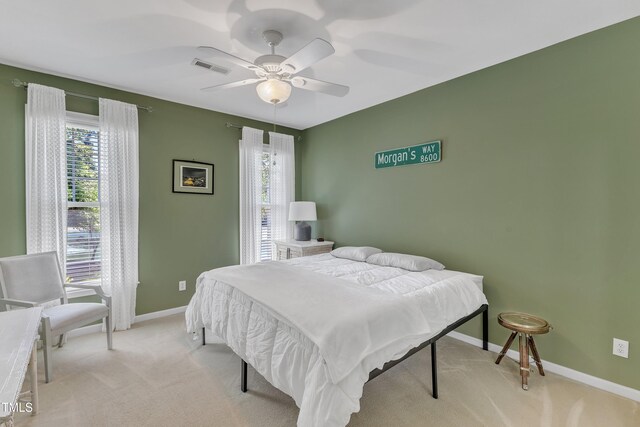 bedroom with multiple windows, light colored carpet, baseboards, and a ceiling fan