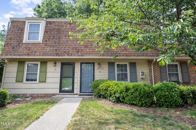 view of front facade with a shingled roof and a front yard