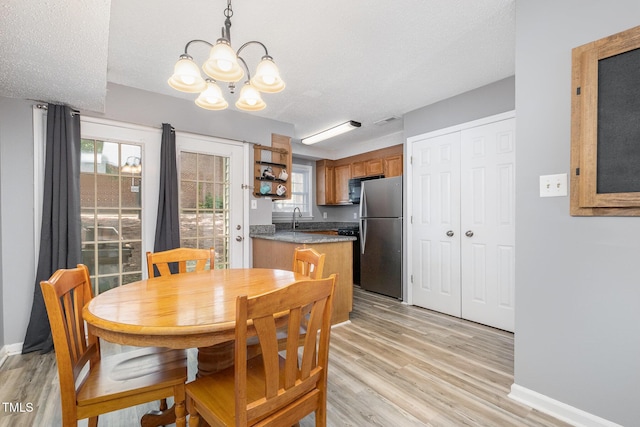 dining space featuring baseboards, a chandelier, and light wood-style floors