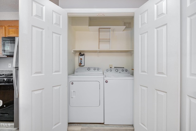 laundry area with visible vents, laundry area, light wood-type flooring, and washing machine and clothes dryer