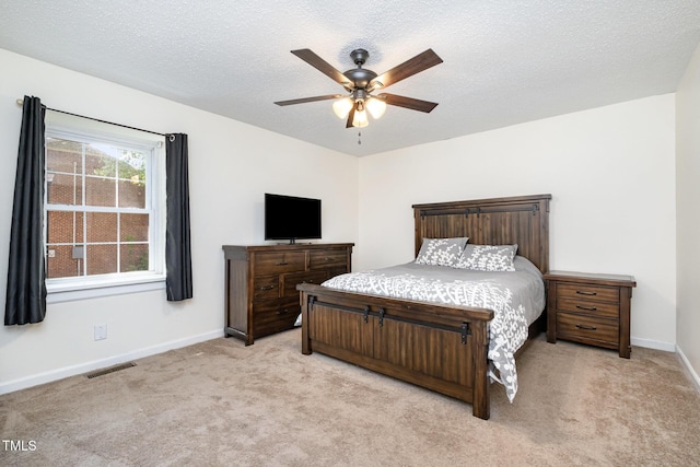 bedroom with light colored carpet, a textured ceiling, a ceiling fan, baseboards, and visible vents