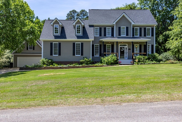colonial-style house featuring a porch, a front yard, roof with shingles, and driveway
