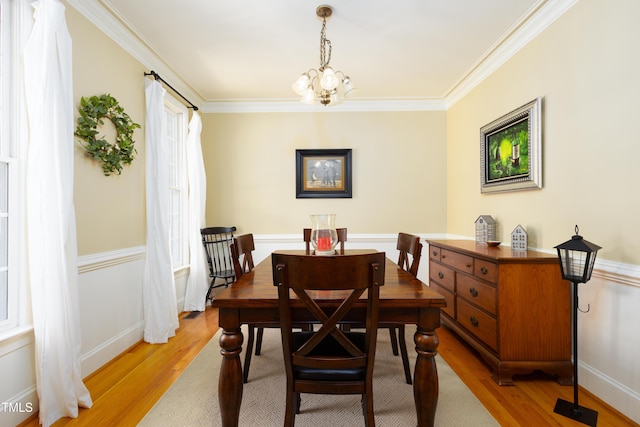 dining area featuring a chandelier, light wood finished floors, ornamental molding, and baseboards