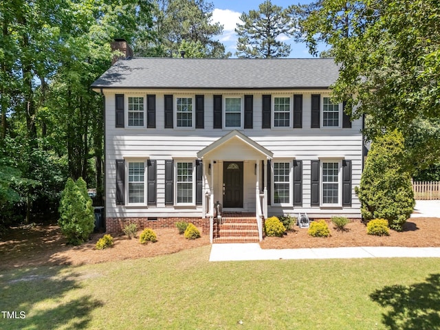 colonial home with a front lawn, a chimney, crawl space, and a shingled roof