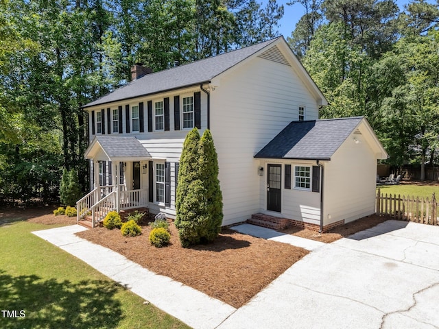 colonial-style house with a chimney and roof with shingles