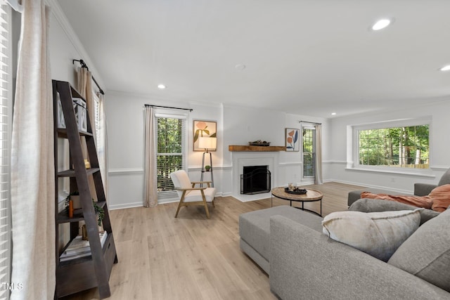 living room with a fireplace, light wood finished floors, recessed lighting, crown molding, and baseboards