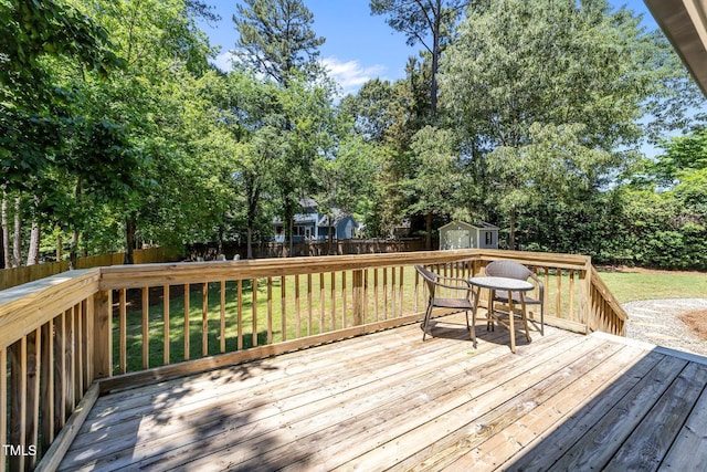 wooden terrace with a shed, an outdoor structure, and view of wooded area