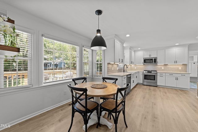 dining room with light wood-style flooring, recessed lighting, crown molding, and baseboards