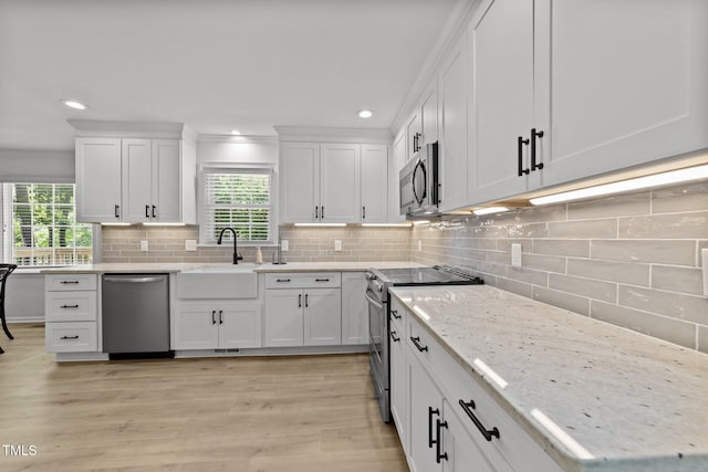 kitchen with stainless steel appliances, a sink, white cabinetry, healthy amount of natural light, and recessed lighting