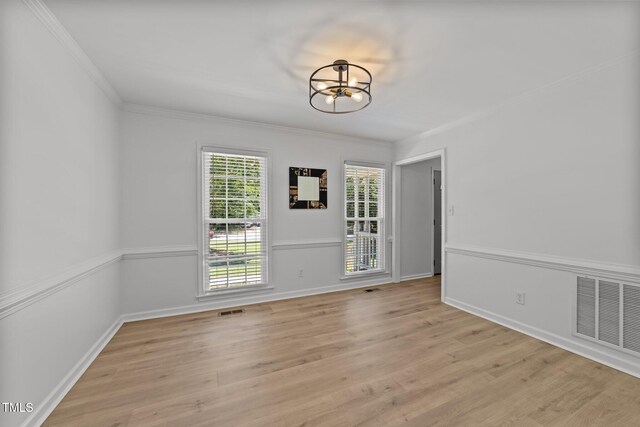 unfurnished dining area with a chandelier, ornamental molding, light wood-style floors, and baseboards