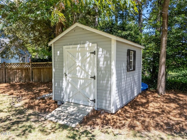 view of shed featuring fence and view of wooded area