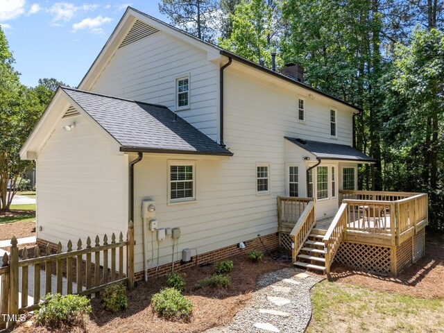 back of house with roof with shingles, a chimney, fence, a wooden deck, and crawl space