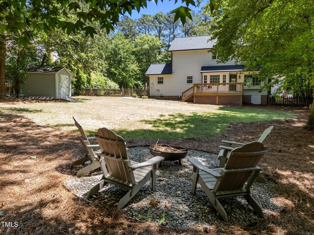 view of yard featuring an outdoor fire pit, a wooden deck, a storage shed, and an outbuilding