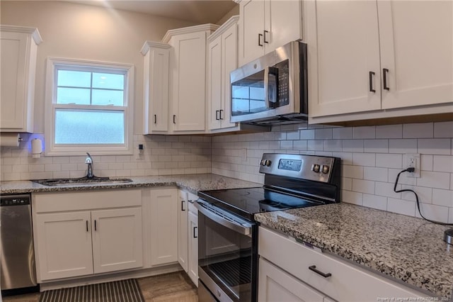 537 Kivett Ct, Fayetteville, NC 28312 - kitchen featuring decorative backsplash, light stone countertops, white cabinets, a sink, and appliances with stainless steel finishes