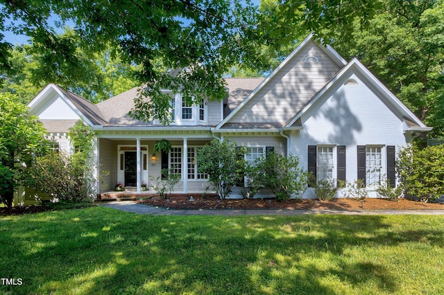 view of front of house with a front yard, covered porch, and a shingled roof
