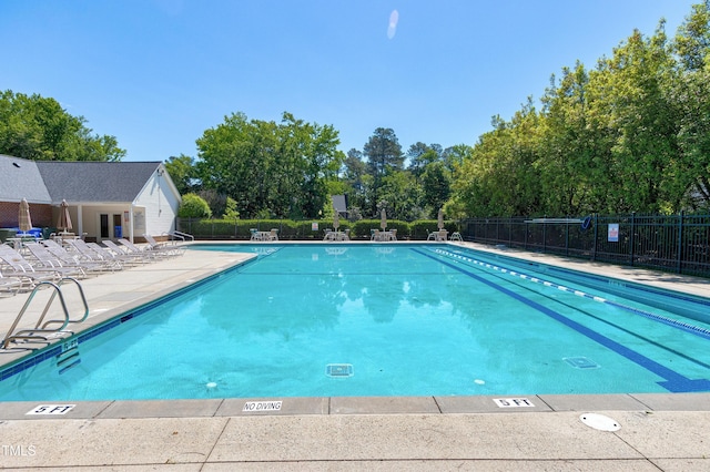 community pool with fence, a patio area, and view of scattered trees